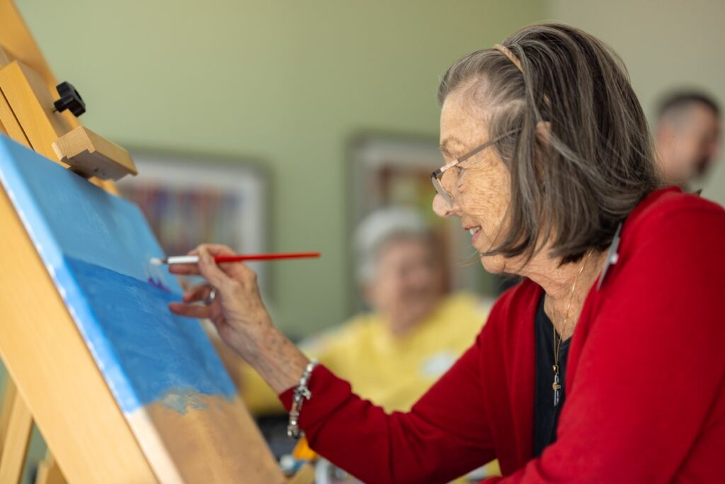 Senior woman painting on canvas during an activity.