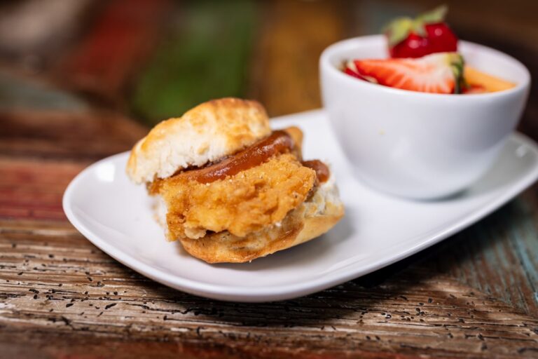 A biscuit sandwich with strawberries on the side.