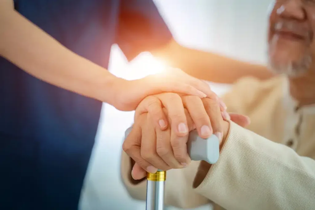 Close-up of a caregiver holding a senior's hand