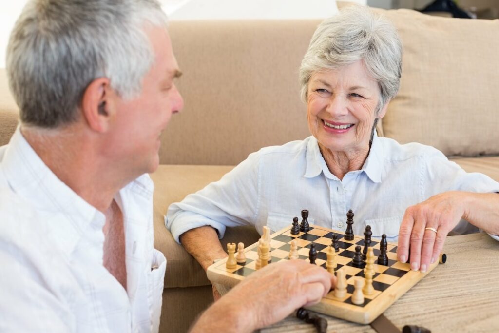 Two seniors playing chess together indoors