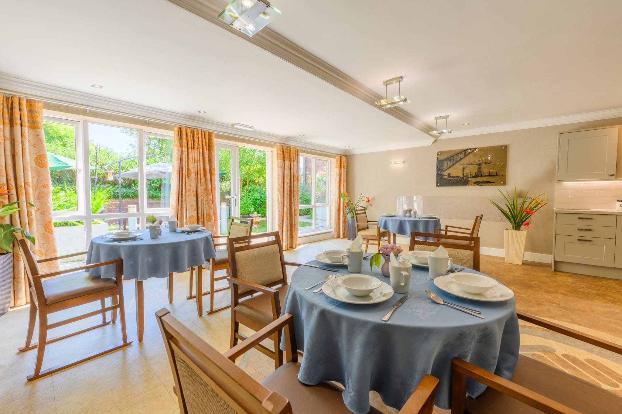 Well-lit dining room with set tables and views of greenery.