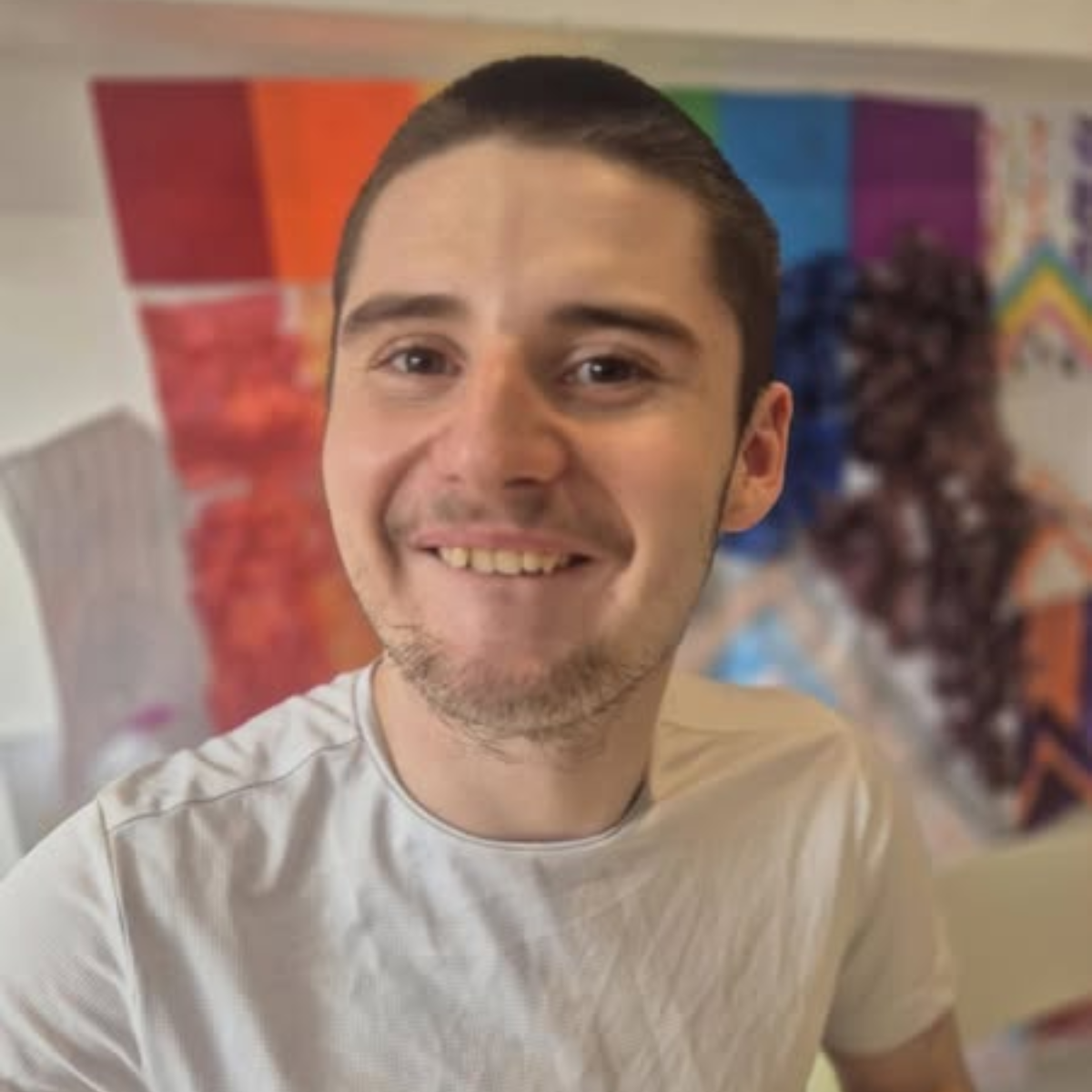 A smiling young man in a colorful room.