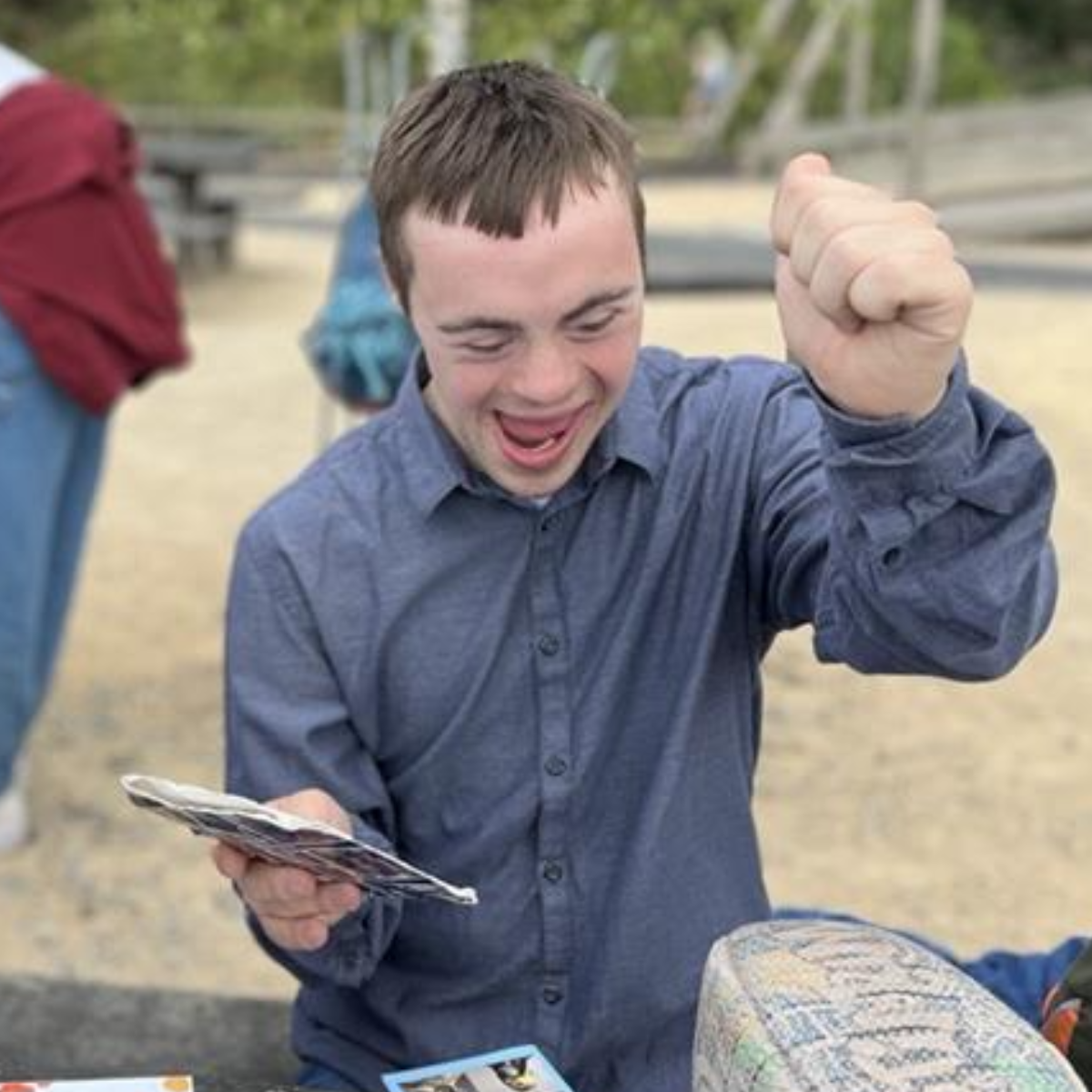 Young man excitedly holding photos outdoors.
