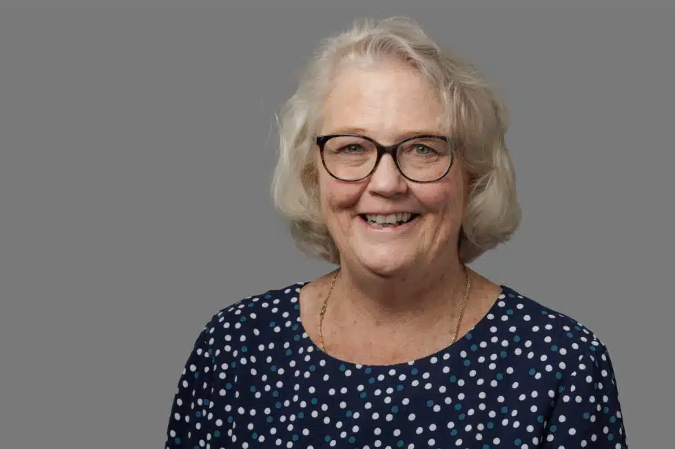 Smiling woman with glasses wearing a polka dot blouse