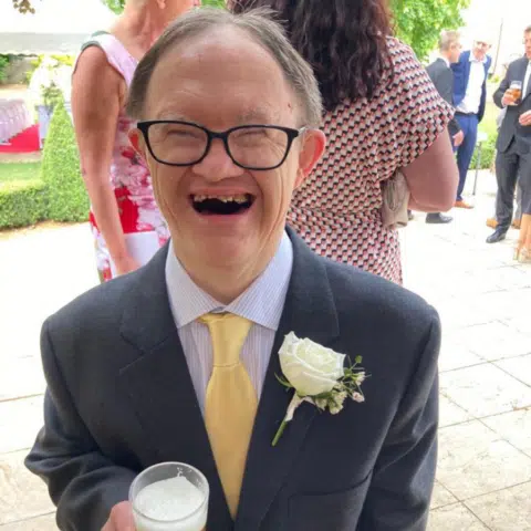 Man smiling at a social event wearing formal attire.