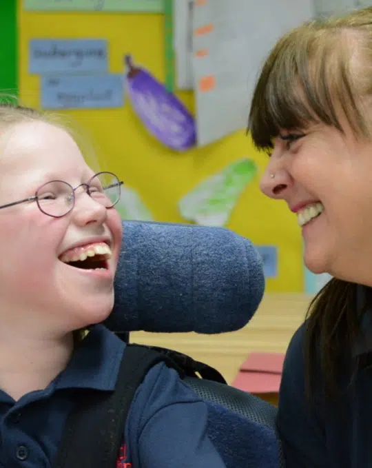 Smiling girl in wheelchair with caregiver
