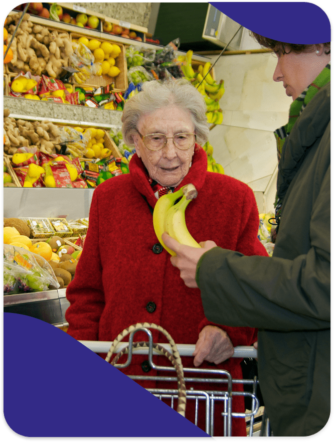 Elderly woman choosing bananas in a market.