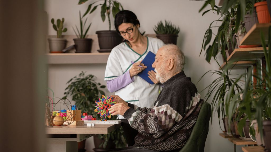 Caregiver assisting an elderly man with an activity.