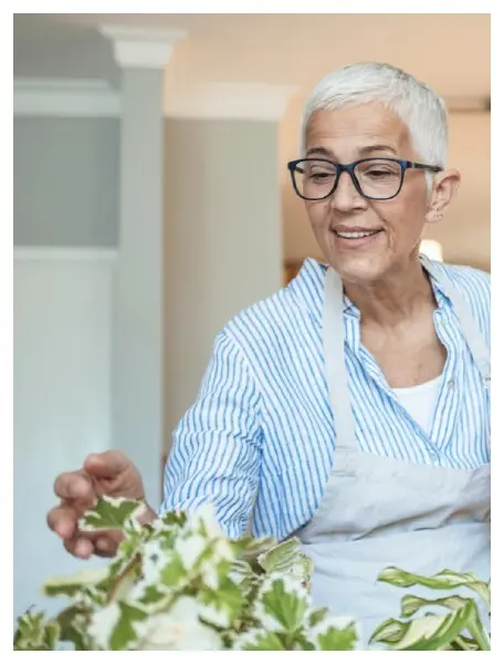 A smiling senior woman arranging plants indoors
