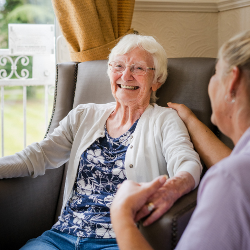 Smiling elderly woman enjoying time with a caregiver.