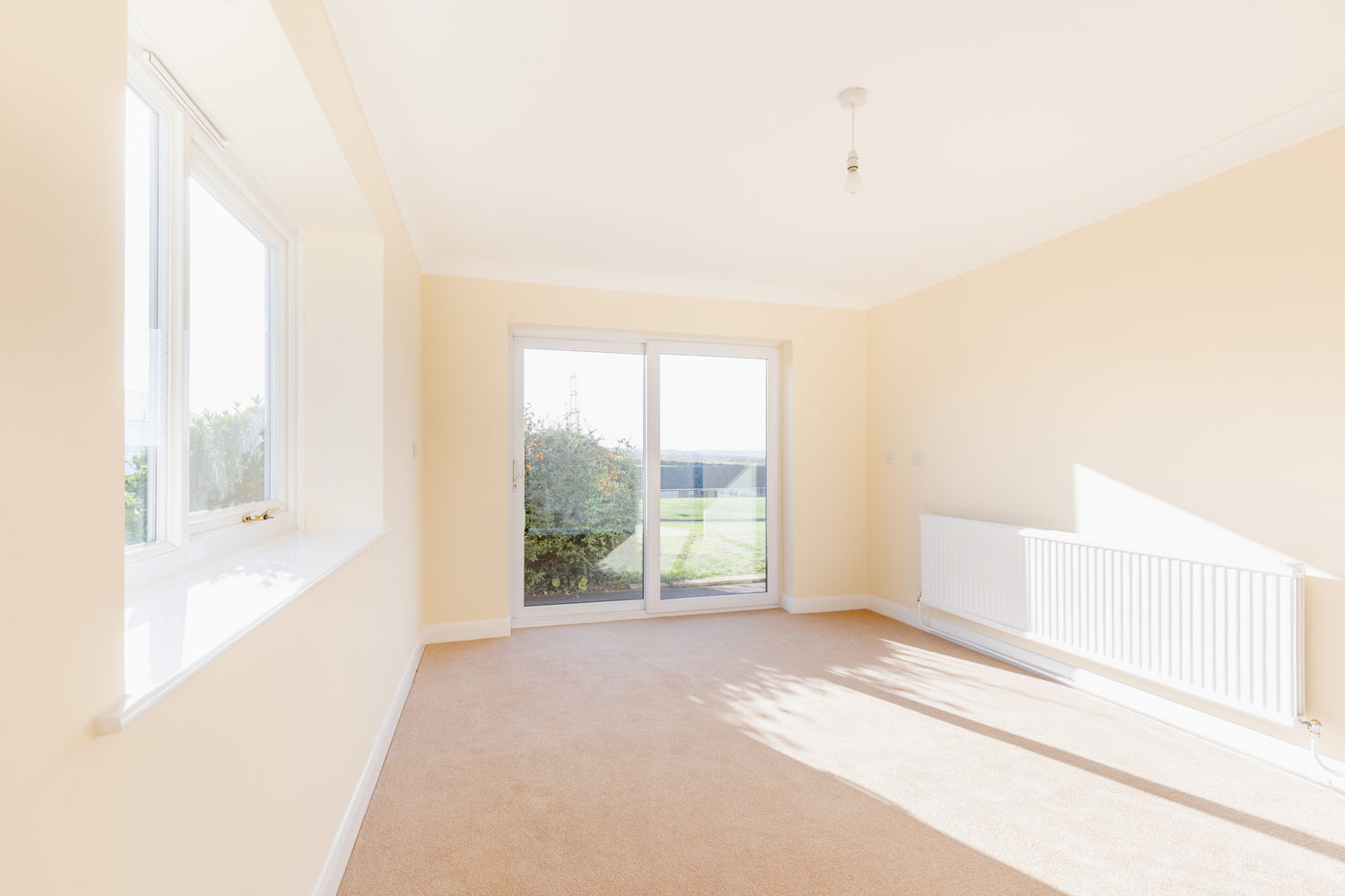 Bright, empty room with carpet and sliding doors.