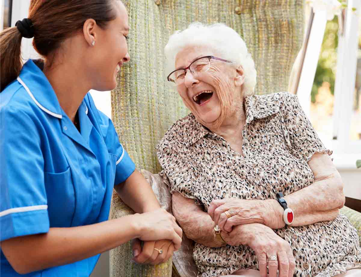 A caregiver laughing with a resident in a chair