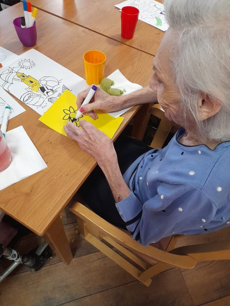 Resident coloring at a table with art supplies.