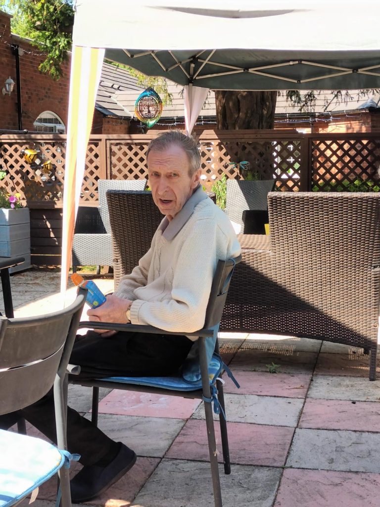 Resident sitting outdoors in a garden area.