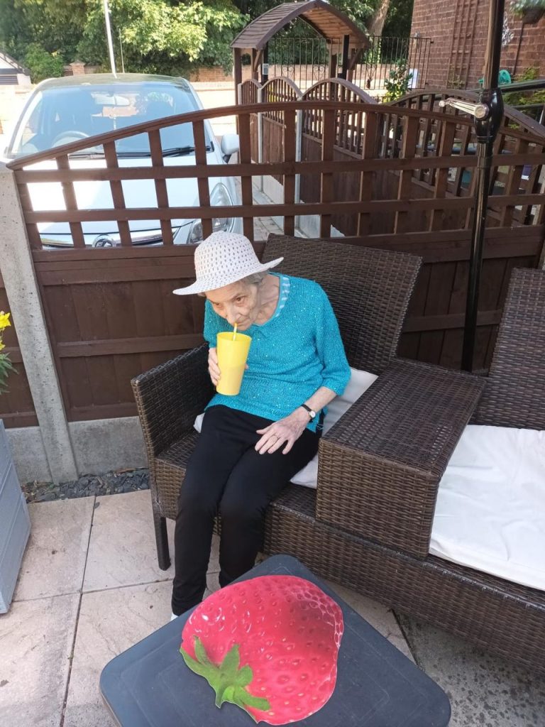 Resident enjoying a drink in a garden setting.