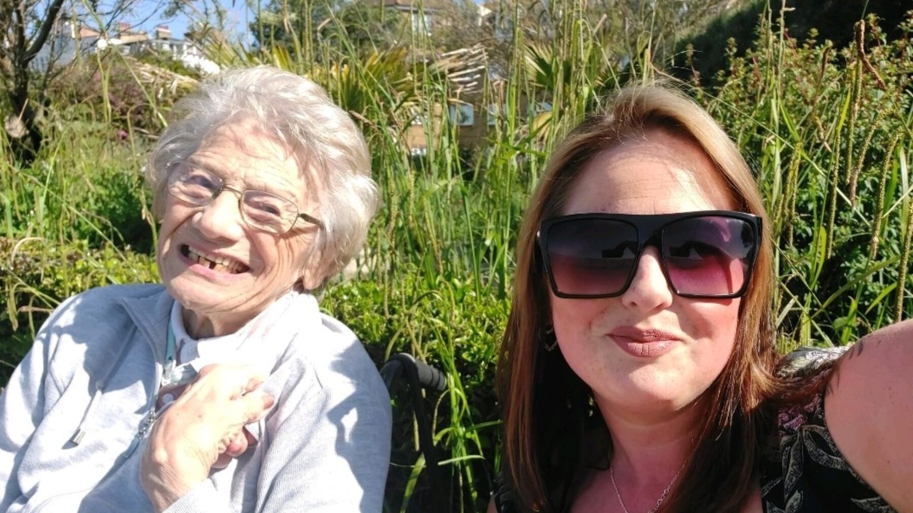 A resident and staff member smiling outdoors.