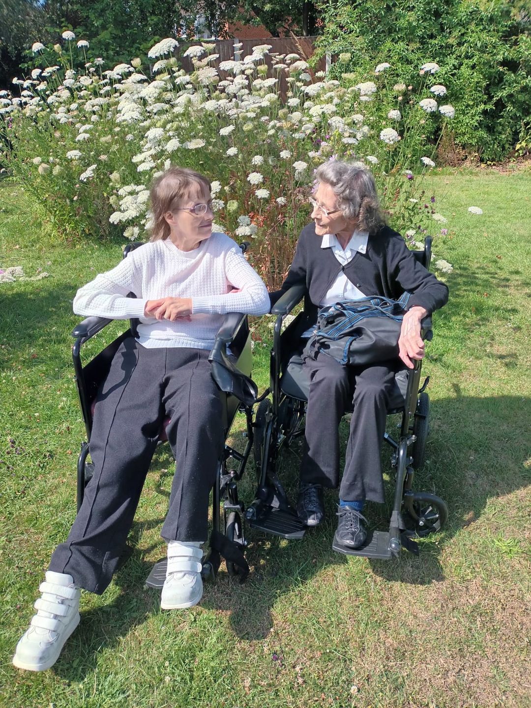 Two women in wheelchairs enjoying the garden