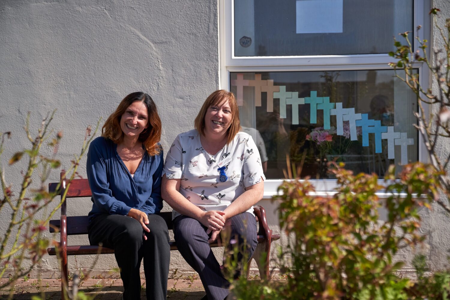 Two staff members sitting outside on a bench.
