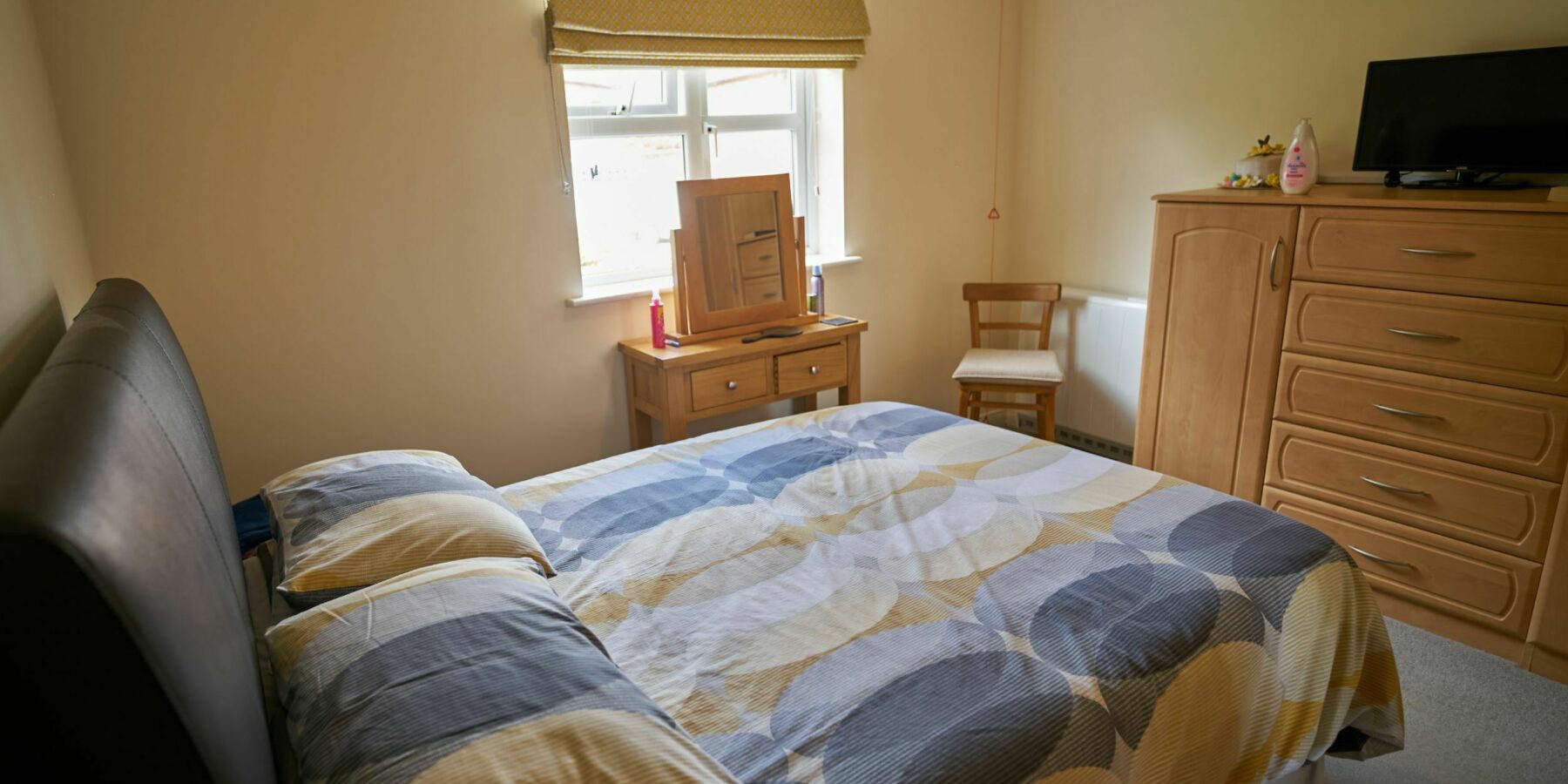 Cozy bedroom with a patterned bedspread and furniture.