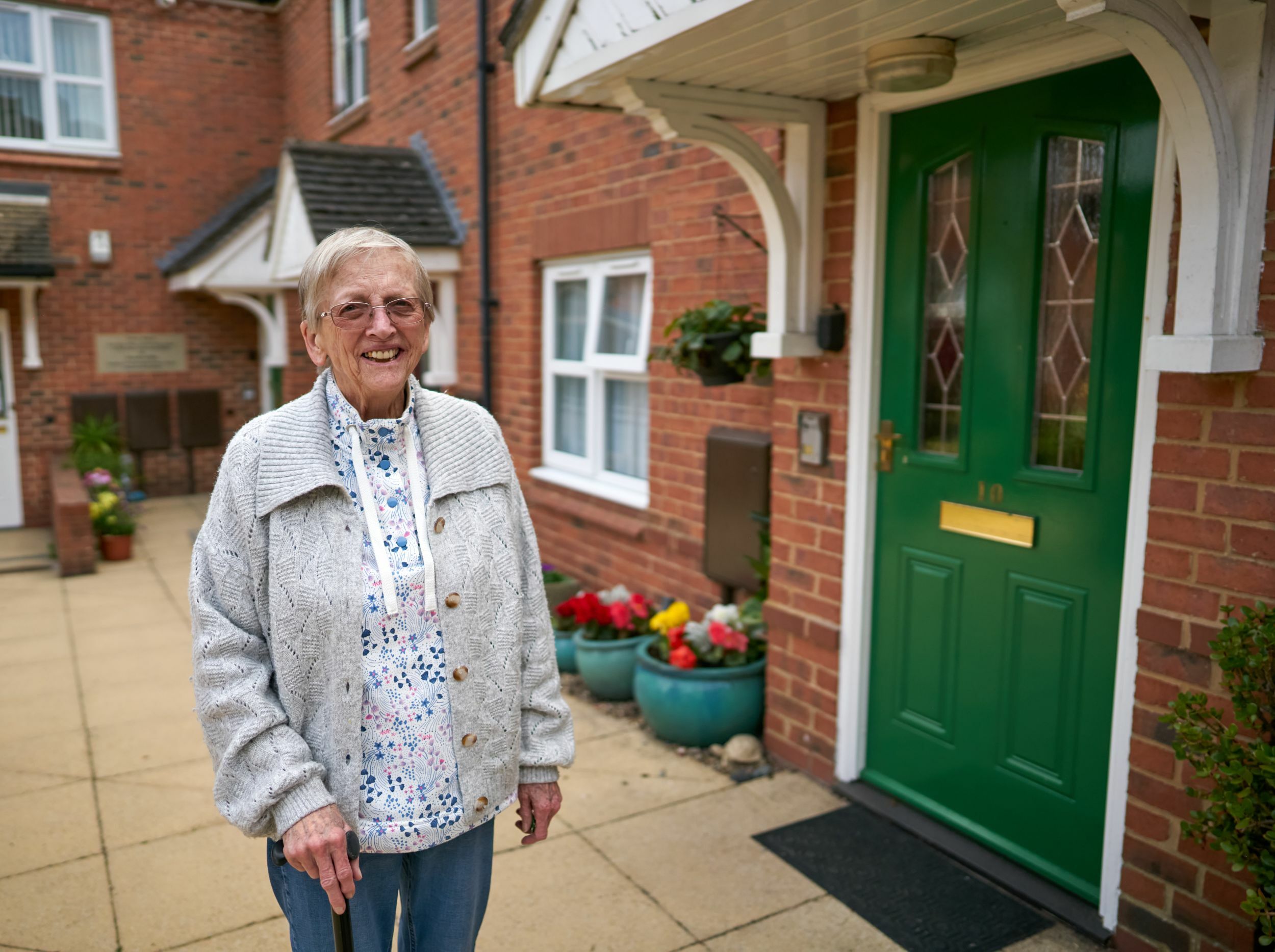 Elderly woman standing outside a green door