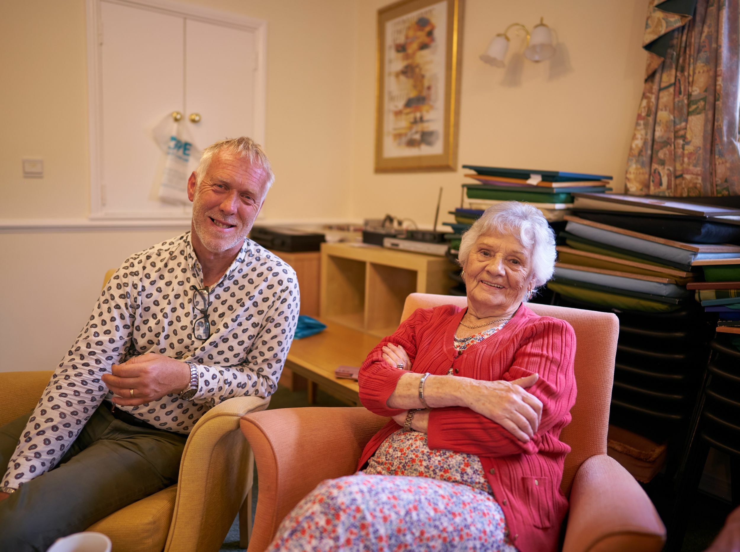 A staff member and resident smiling in a cozy interior.