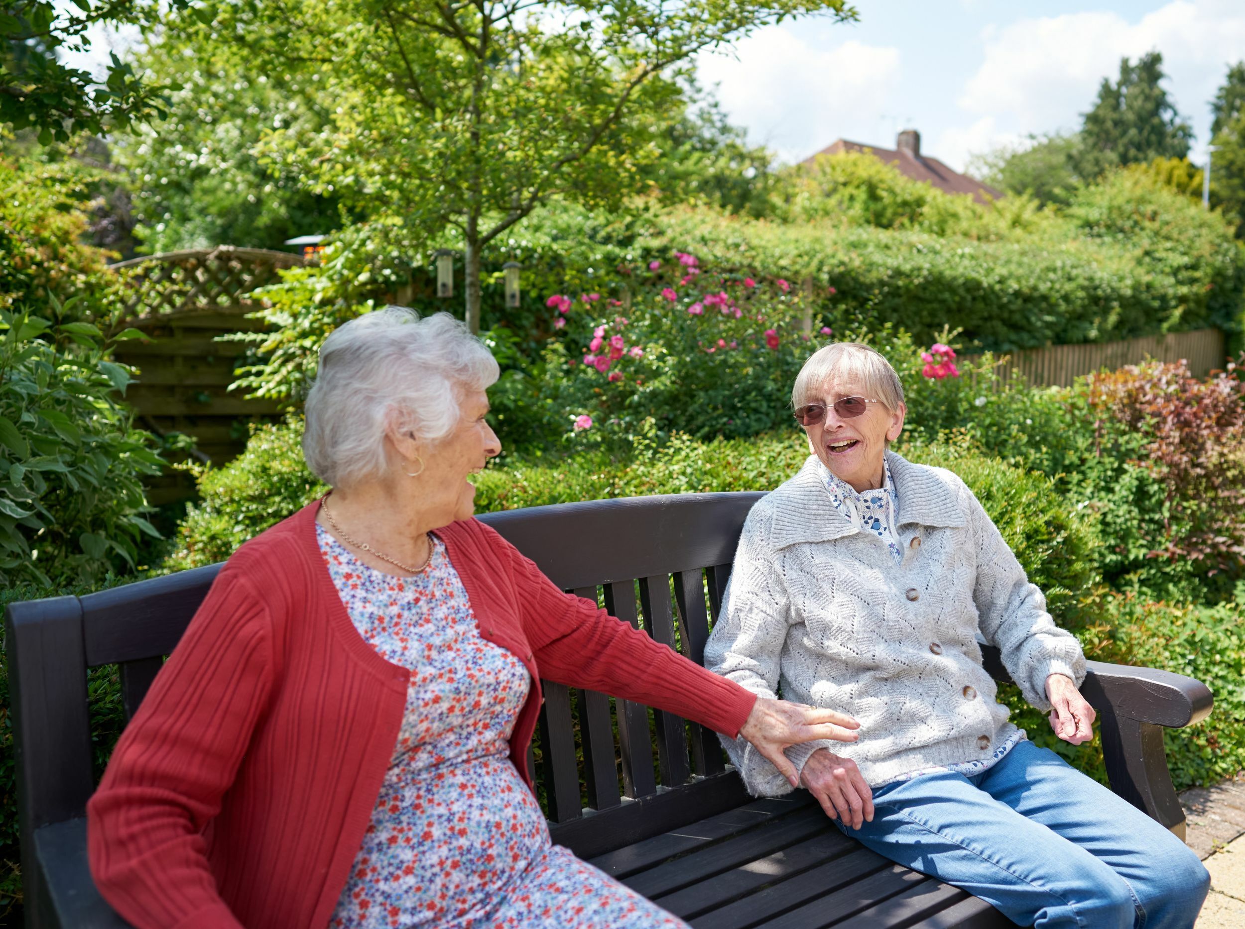 Two elderly women enjoying a conversation in a garden.