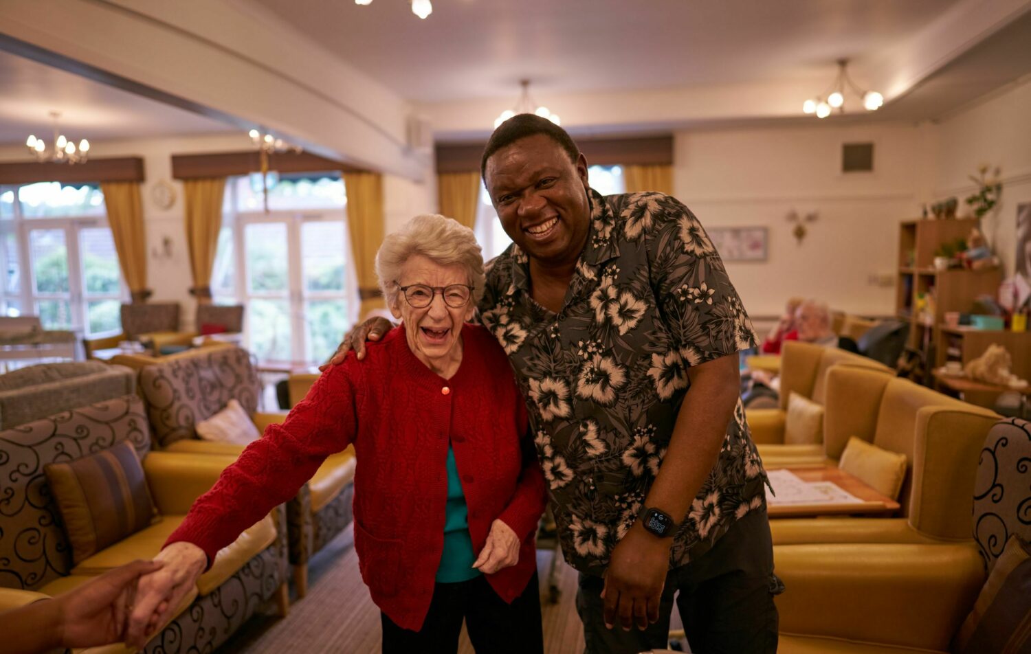 A resident and staff member smiling in a common area.