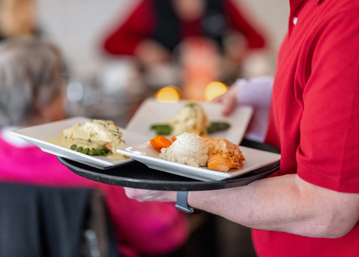 Staff serving meals to residents in a dining area