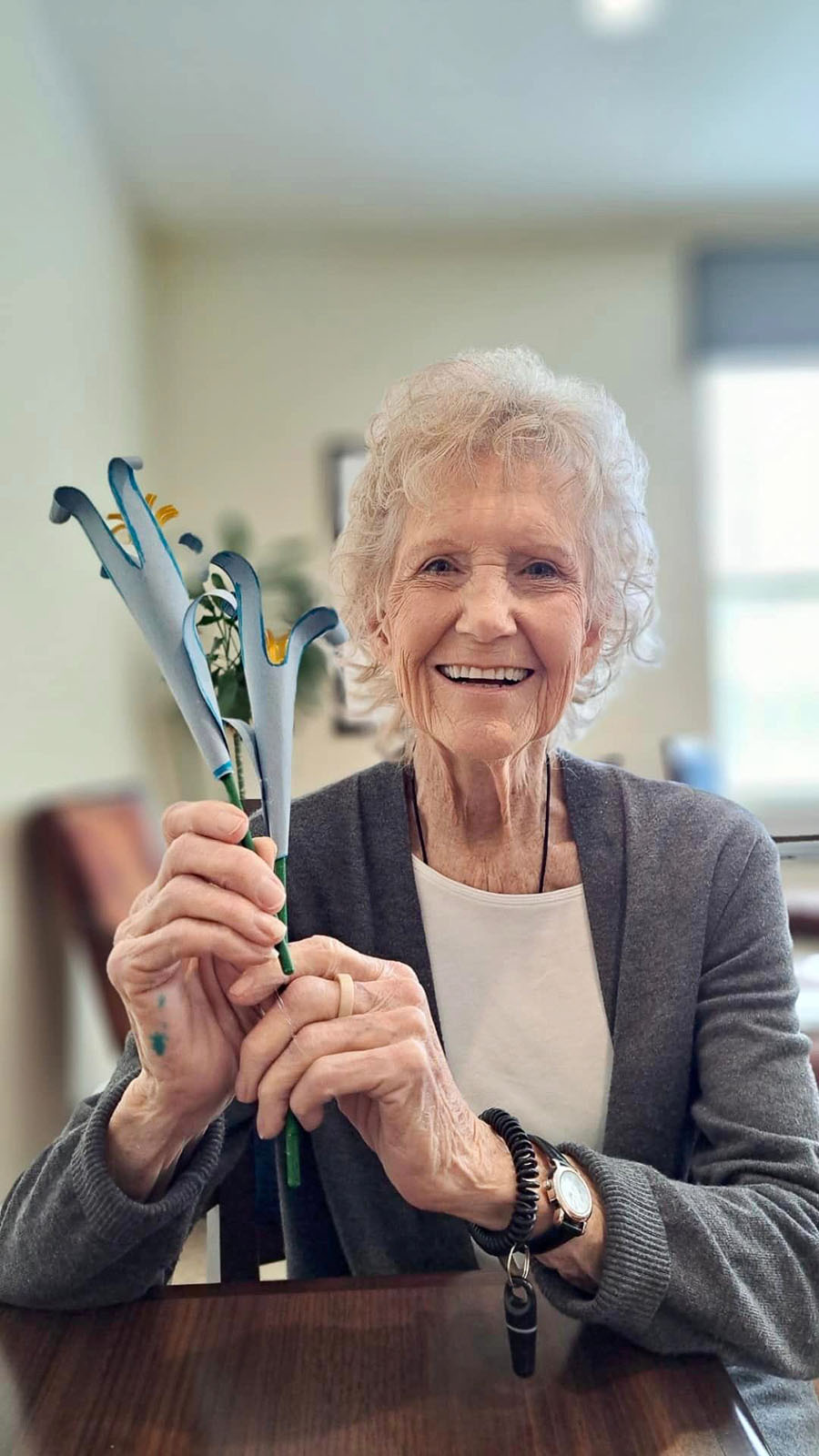 Resident holding handcrafted flowers, smiling warmly