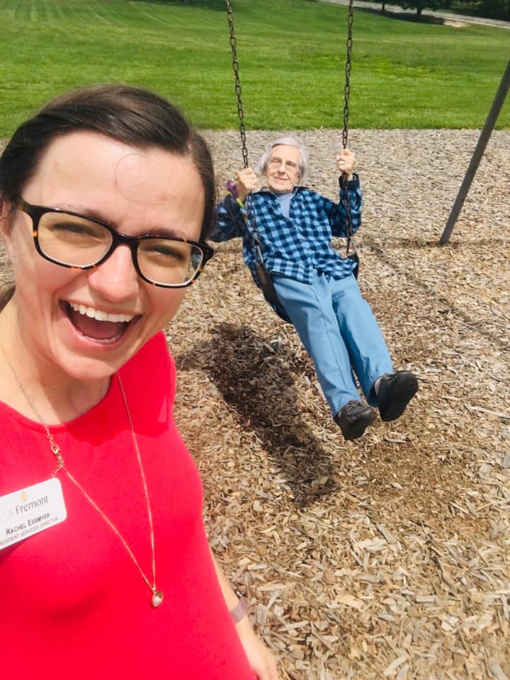 Staff member swinging a resident at a park