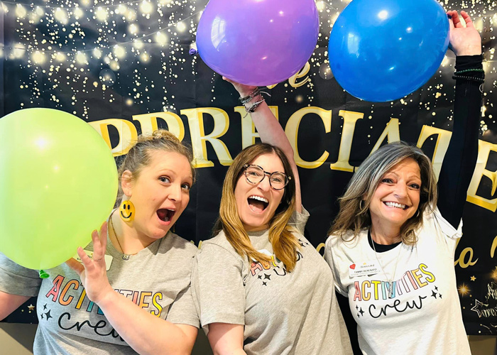 Activity staff celebrating with balloons in the common area