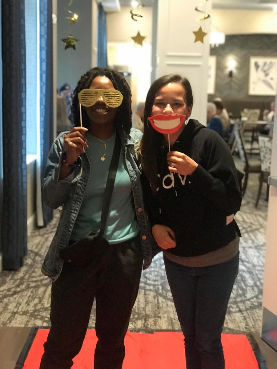Two staff members posing with fun props in a common area