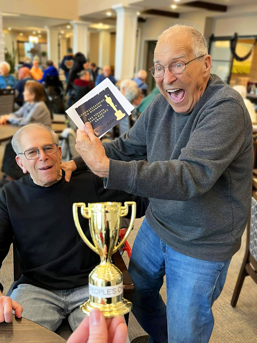 Two male residents celebrating with a trophy in a common area