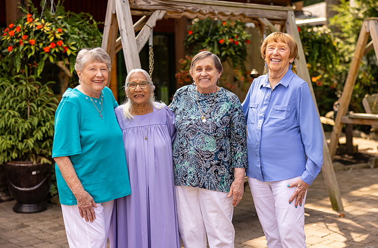Four residents smiling together in a garden area