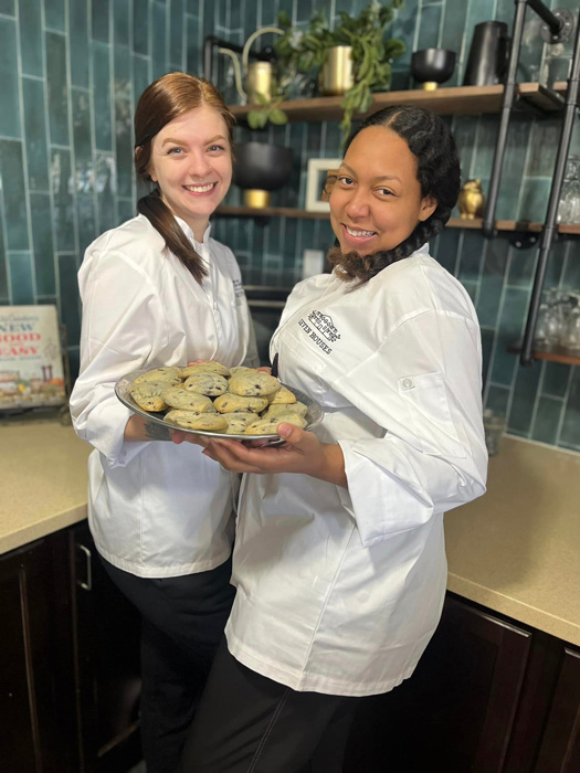 Staff members presenting baked cookies in the kitchen