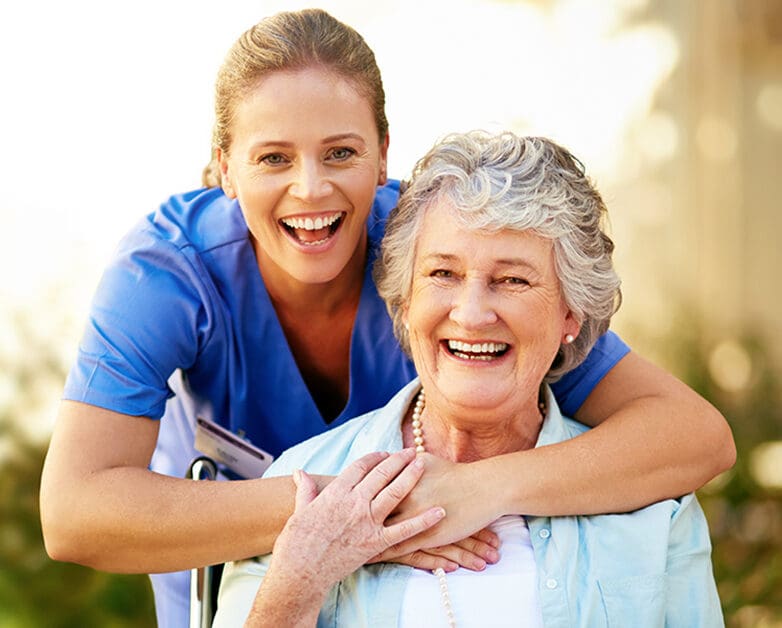 A nurse smiling with a happy resident outdoors
