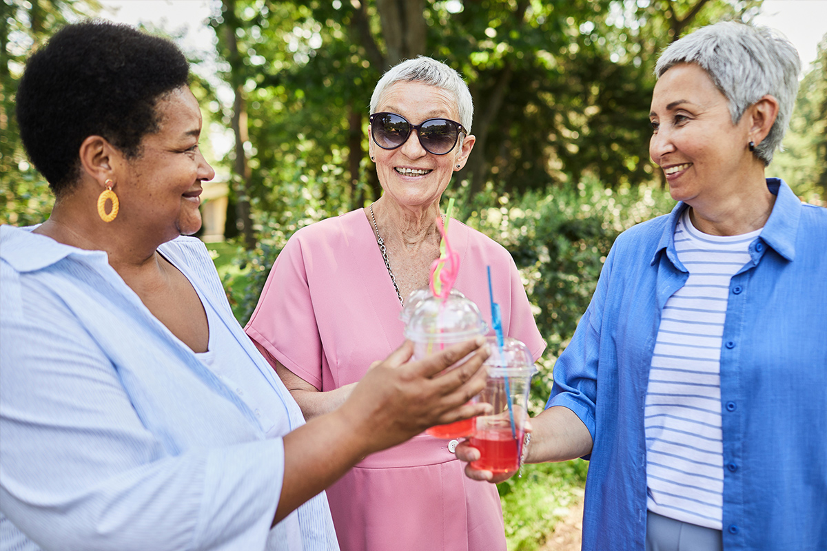 Three women enjoying drinks in a garden.