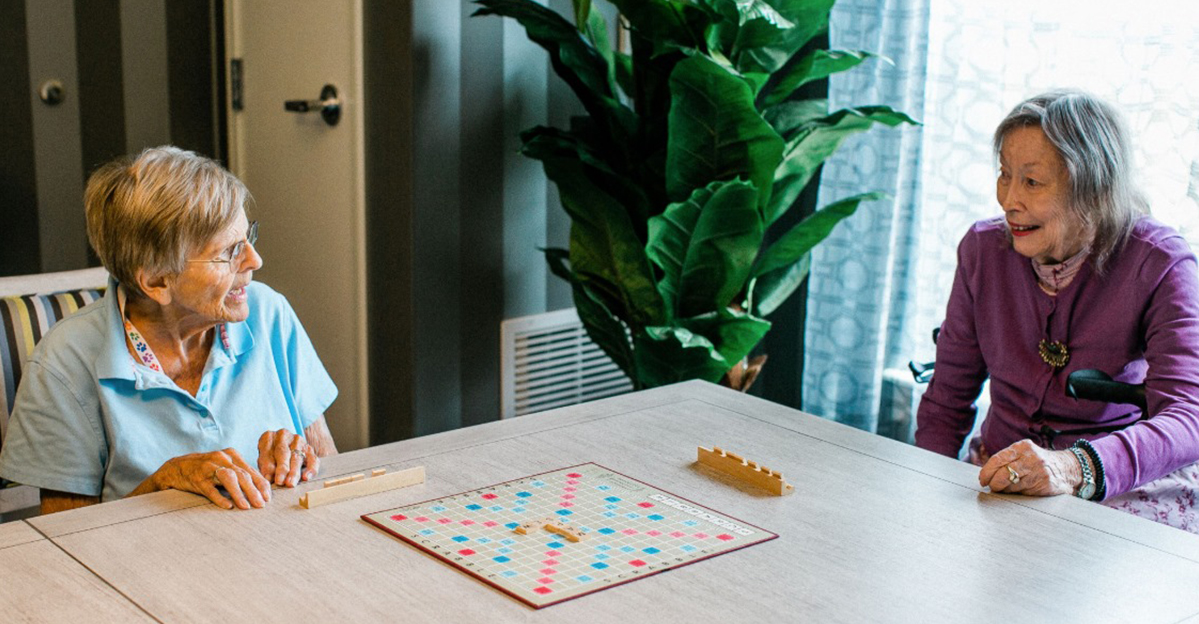 Two residents playing a board game in a bright room