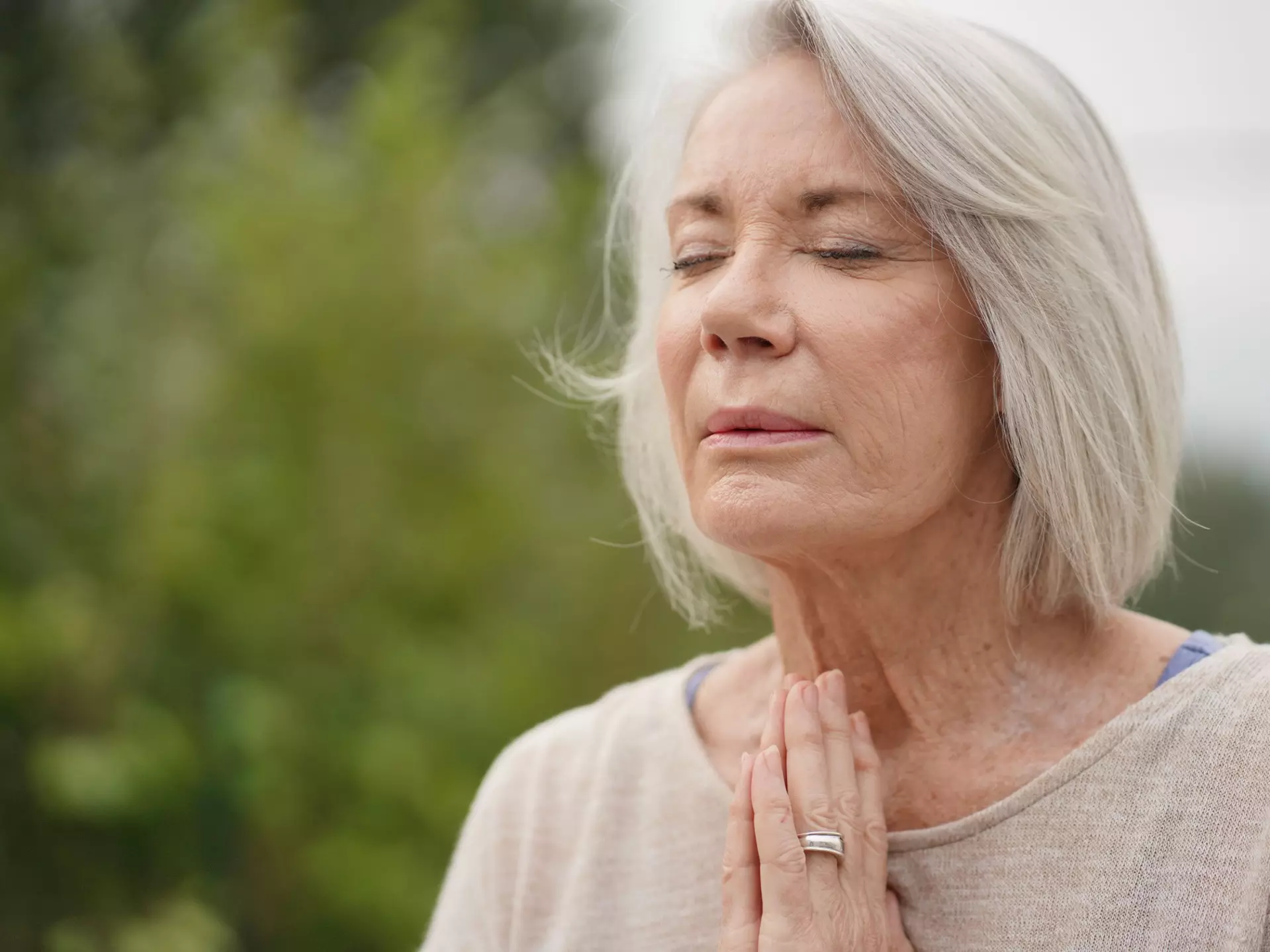 A senior woman with closed eyes in a peaceful outdoor setting