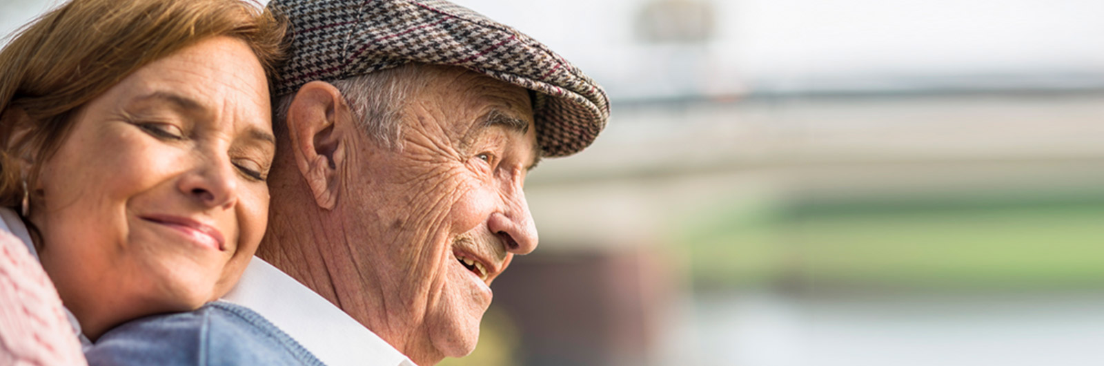 A smiling elderly man and woman enjoying time together outdoors.