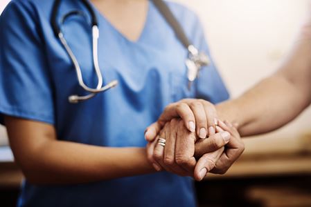 A healthcare professional holding hands with a resident