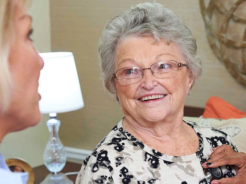 A smiling elderly woman speaking with a staff member