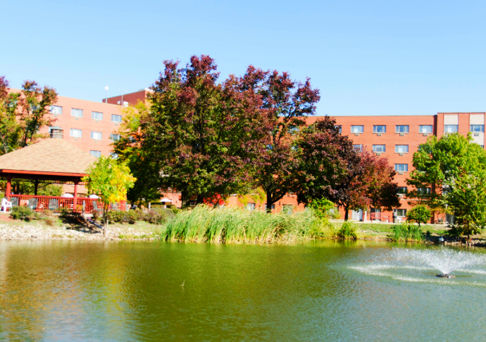 Exterior view of the facility with a pond and trees
