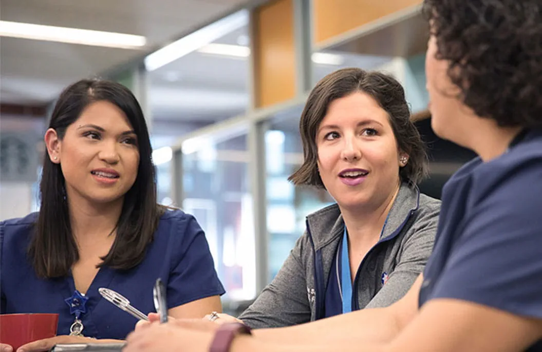Three staff members engaged in conversation