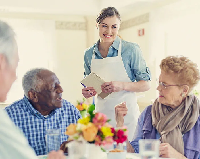 Residents enjoying a meal with staff in a dining area