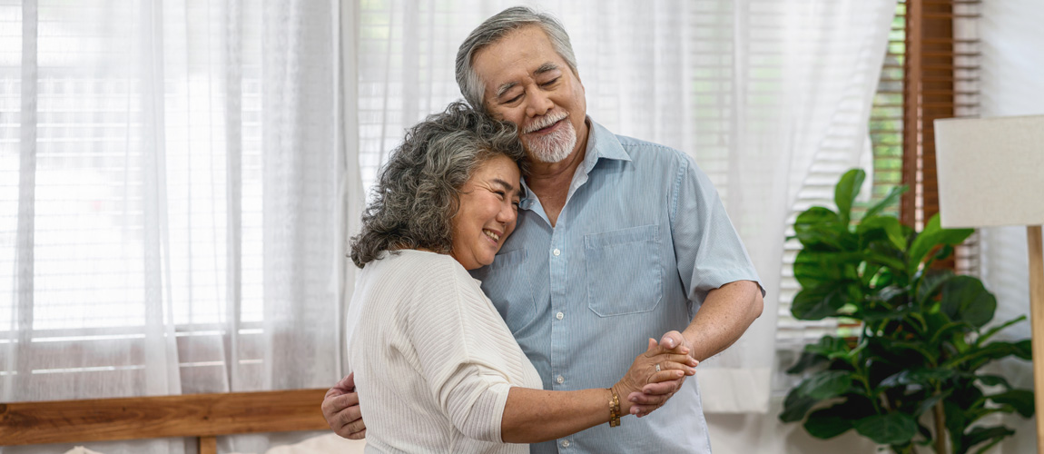 Happy elderly couple dancing indoors