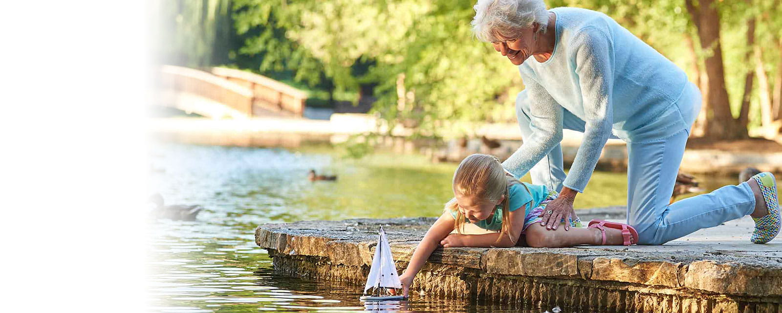 Senior woman and young girl playing by the water