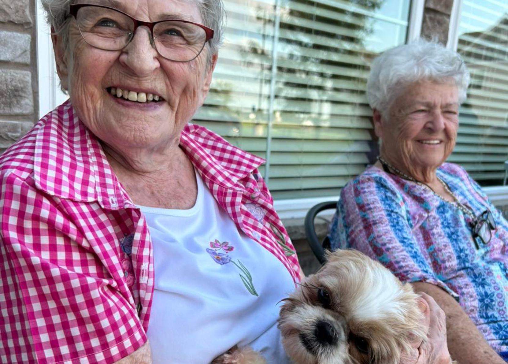 Two smiling residents enjoying time outdoors with a dog