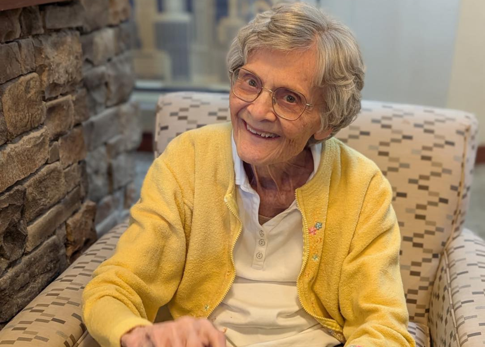 Resident smiling in a cozy chair in the facility