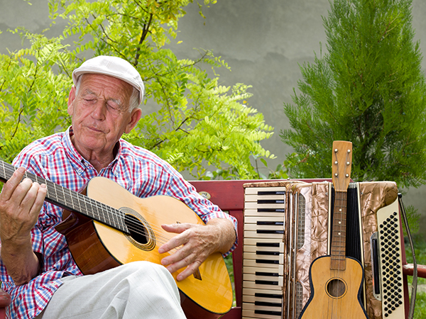 Senior man playing guitar outdoors in a garden
